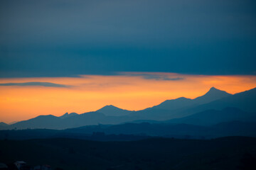 Silhouetted mountains at dusk under a dramatic orange sky