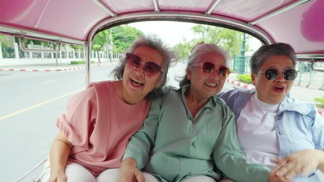 4K Happy Asian senior woman travel city street on summer holiday vacation. Group of Elderly women friends enjoy and fun outdoor lifestyle travel Bangkok city by three wheeled vehicles Tuk Tuk taxi.