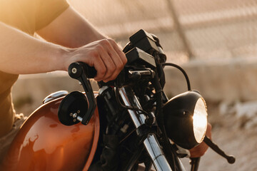 Biker holding handlebars of a custom motorcycle at sunset