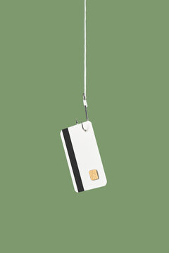 Bank card hanging on fishing hook over green studio background
