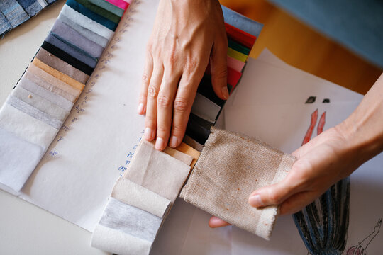 Top view of copped designer choosing colors for clothes at table