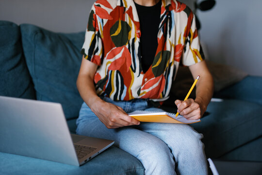 Cropped student or entrepreneur using laptop and writing in copybook