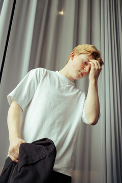 Young man pondering in casual attire under soft lighting