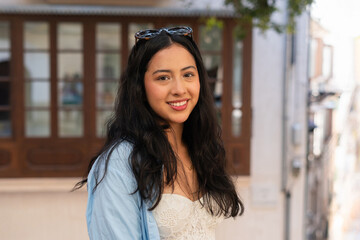 A smiling woman is sightseeing in the city on a sunny day