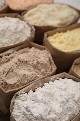 Paper sacks with different types of flour as background, closeup