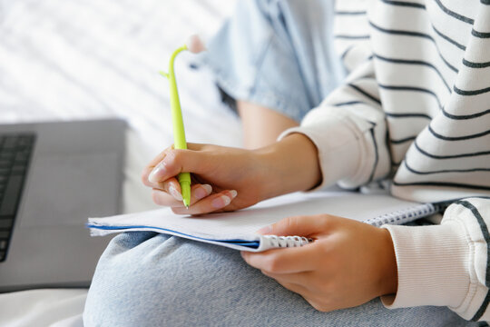 Cropped of female school student writing in notebook with pen at home
