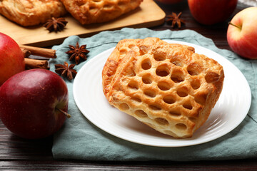 Delicious puff pastries, apples, cinnamon and anise stars on wooden table, closeup