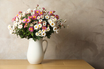 Vase with beautiful flowers on pink wooden table. Space for text