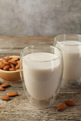 Fresh nut milk in glasses and almonds on wooden table, closeup