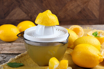 Juicer and fresh lemons on wooden table