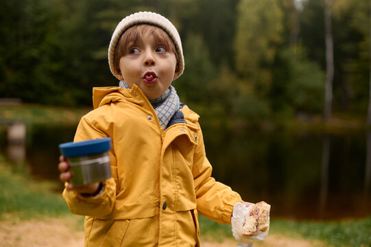 funny portrait of a little boy with a cup of tea outdoors