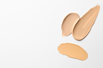 Samples of foundations on white background, top view