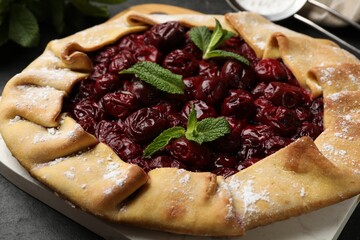 Tasty galette with cherries and mint on grey table, closeup