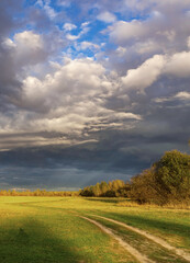 Cloudy sky with a road in the middle of a field