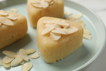 Pieces of delicious semolina halva with almond flakes on white table, closeup