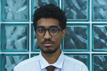 Portrait of a Man Wearing Glasses in Front of Glass Blocks