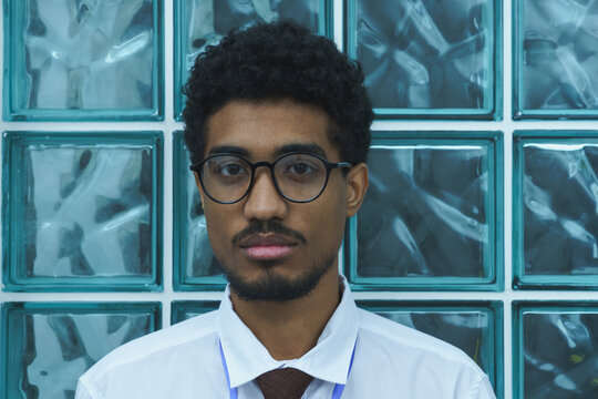 Portrait of a Man Wearing Glasses in Front of Glass Blocks