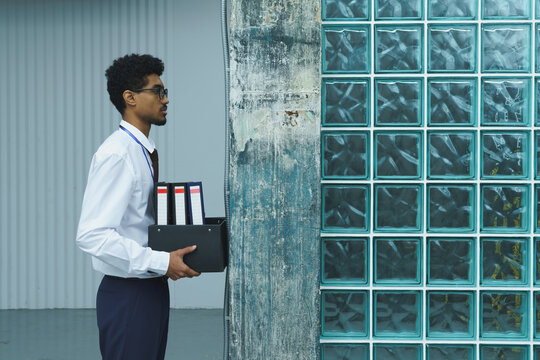  Man Holding File Box Near Glass Block Wall
