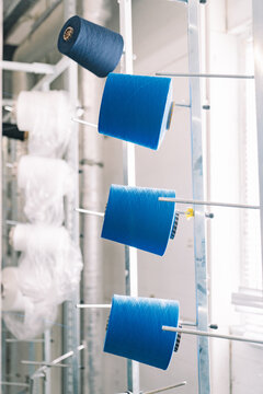 Bright blue spools of thread hanging in a textile workshop