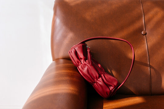 Stylish maroon leather handbag on sofa
