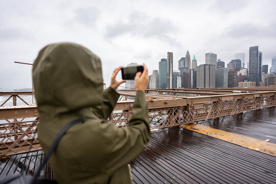 Tourist taking photos of New York City skyline from Brooklyn Bridge