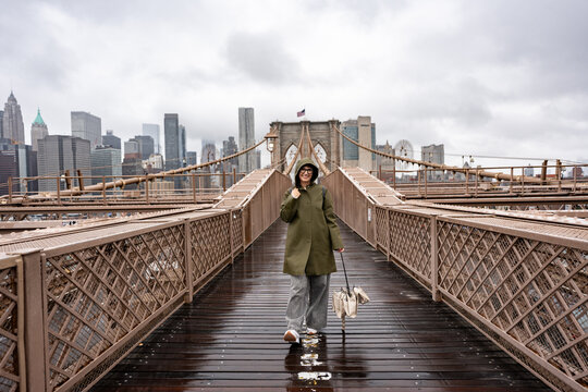 Tourist walking on Brooklyn Bridge in New York City during a rainy day