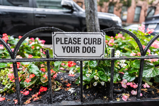 Please curb your dog sign hanging on a fence in New York City