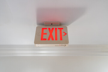 Red Exit Sign Hanging on White Ceiling in New York