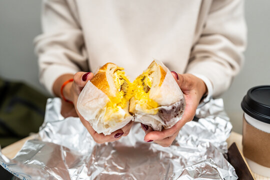 Woman holding a delicious bacon, egg and cheese bagel in New York