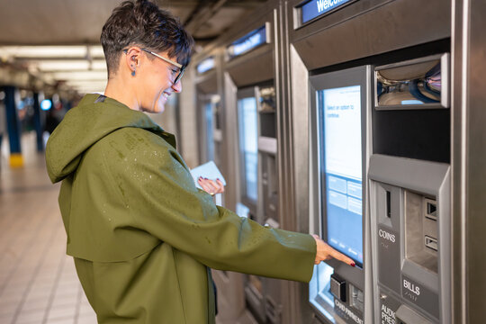 Woman buying metro ticket at automatic machine in New York City Subway
