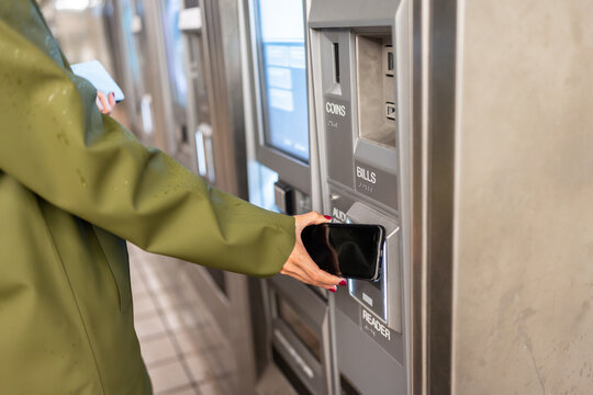 Woman paying with smartphone at ticket machine in New York City Subway