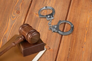 Metal handcuffs with wooden judges gavel