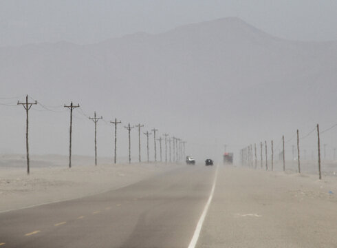 A hot desert road alongside electricity power lines.
