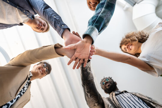 Coworkers joining hands, fostering teamwork and collaboration