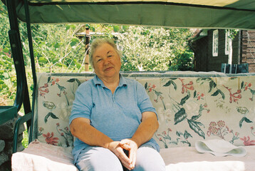 Smiling elderly woman on a garden couch
