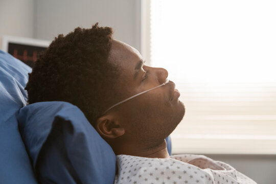 Sick black patient recovering in hospital bed with nasal cannula