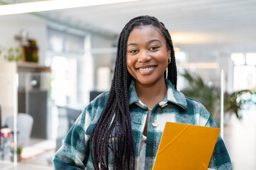 Young black businesswoman smiling and holding a folder
