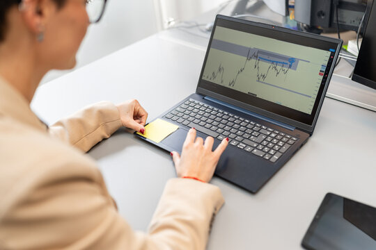 Businesswoman analyzing graph on laptop in coworking space