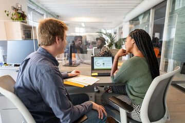 Office workers discussing statistics behind plexiglass
