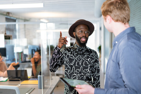 Two businessmen talking and gesturing in modern coworking space