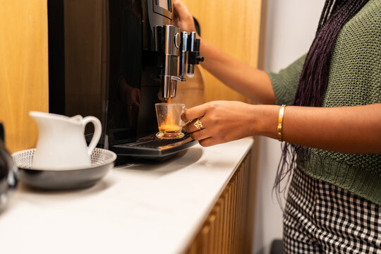 Businesswoman making coffee in modern office during break time