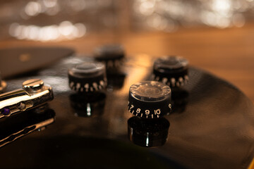 Guitar volume knobs with a reflective surface, warm bokeh background.