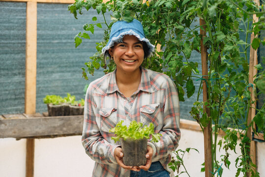 Smiling woman farmer portrait at a greenhouse plating vegetables