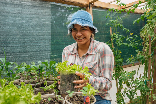 Smiling woman farmer portrait at a greenhouse plating vegetables