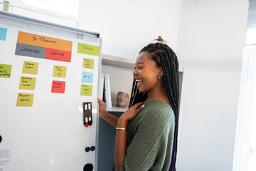 Project manager laughing looking at kanban board in coworking office
