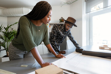 Architects analyzing blueprints in modern coworking office