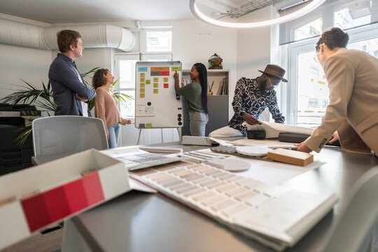 Architects analyzing blueprints and color swatches in coworking office