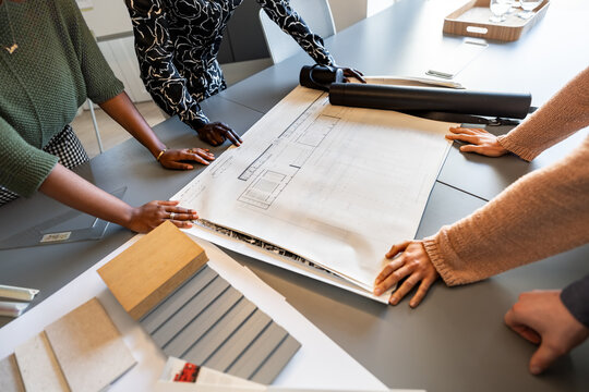 Architects analyzing blueprints and materials in coworking office