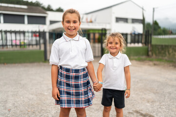 Two smiling students holding hands outside school building