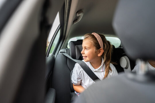 Smiling schoolgirl looking through car window going to school